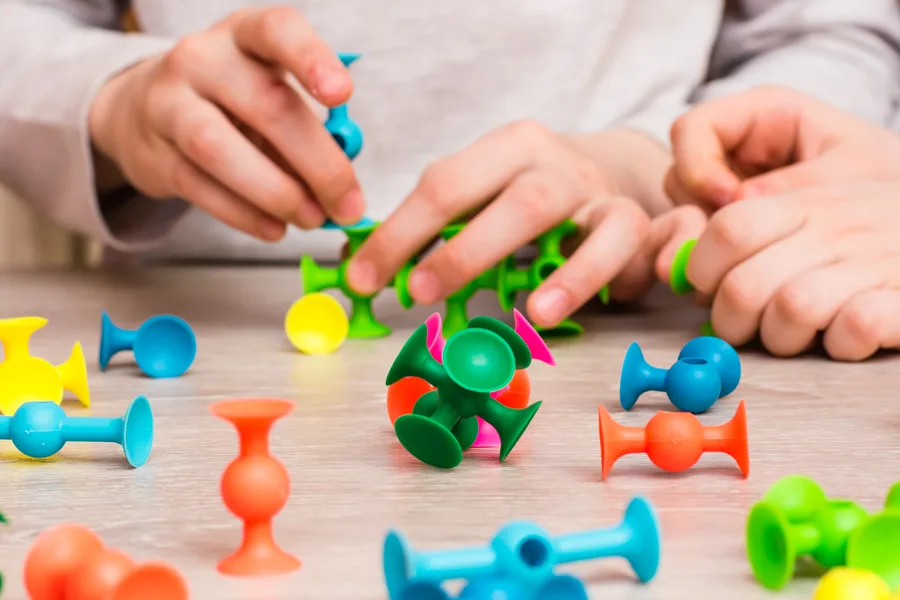 Hands connecting colourful pieces during a fine-motor therapy activity
