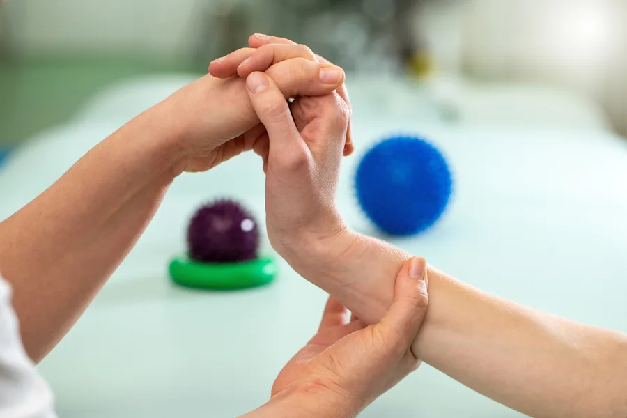 An occupational therapist guiding a client through gentle wrist and hand rehabilitation